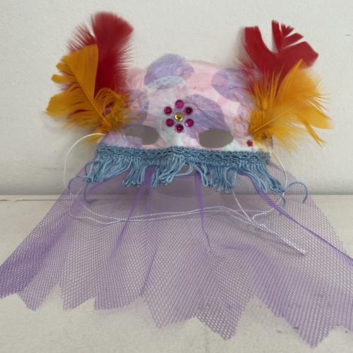 mask decorated with purple net and red and orange feathers
