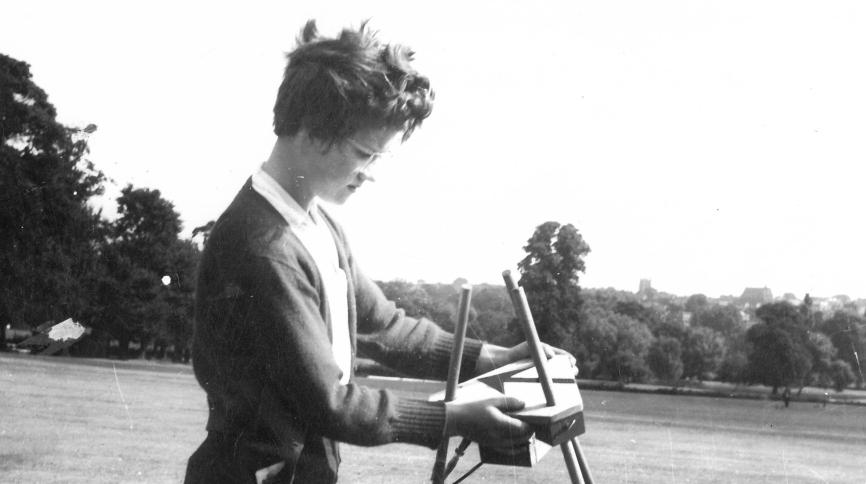 black and white photograph of a woman in a field with short hair and glasses