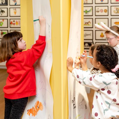 Children drawing at one of the drawing stations in the exhibition
