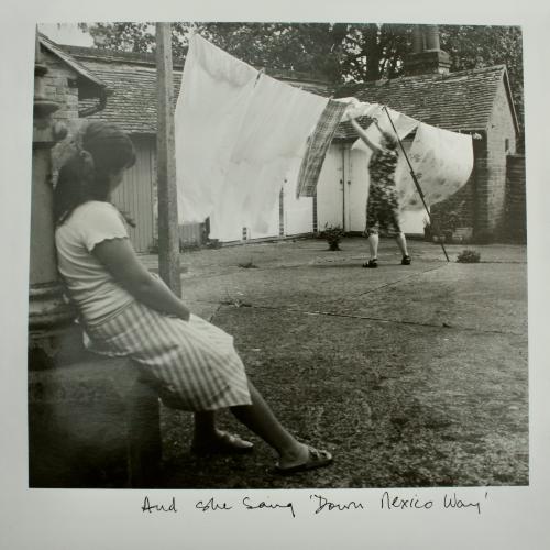 A woman watching someone hang out washing, black and white