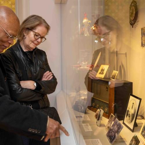 Visitors looking at objects in a case at the Becoming Us exhibition