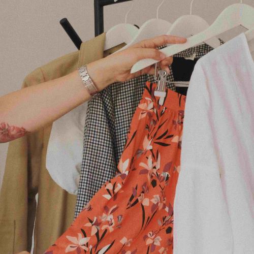 Photograph of hand taking clothes on a hanger off a rail