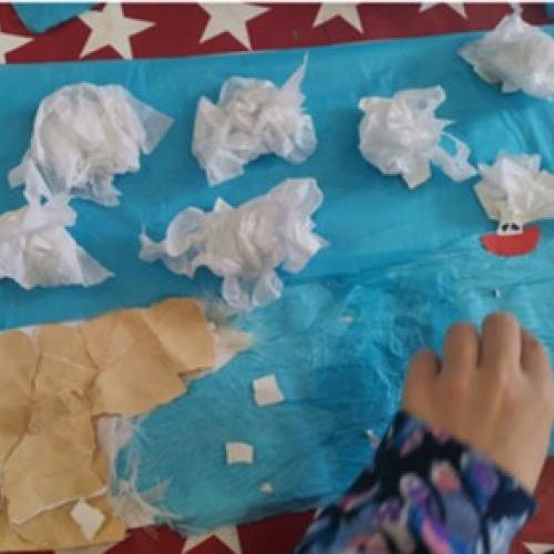 child's hand creating cloudy landscape collage