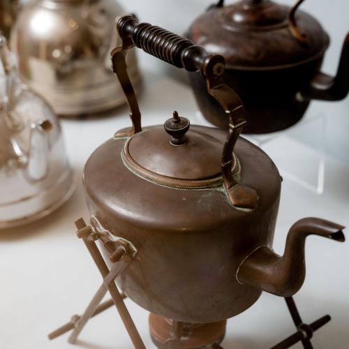 Two copper kettles and two silver kettles on display in the exhibition.