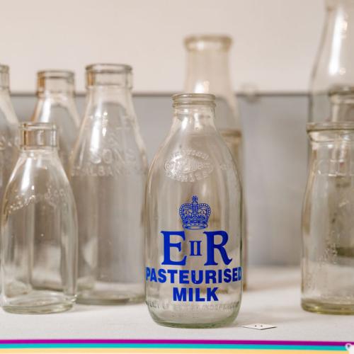 A display of historical glass milk bottles showing various St Albans dairies. One bottle also marked with ER. 
