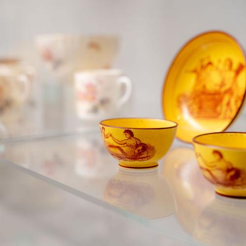 Yellow porcelain tea bowls on display.