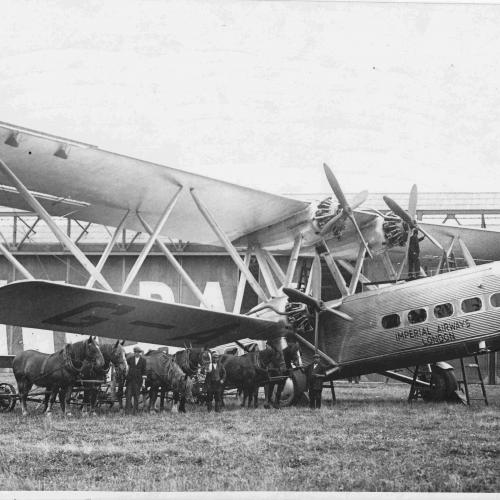 Horse-drawn mowing equipment in front of an HP42 aircraft