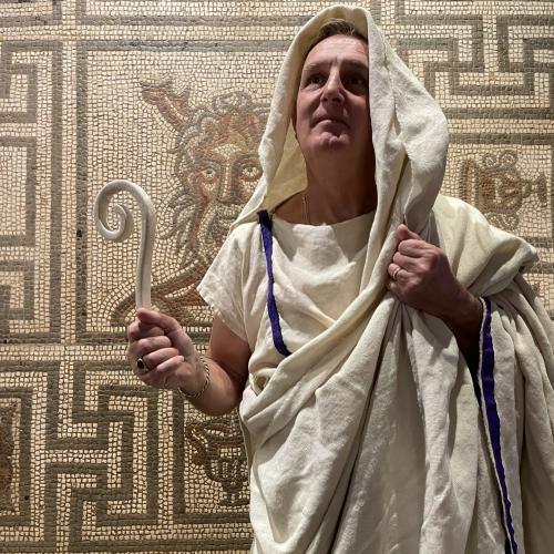 Roman priest re-enactor in front of sea god mosaic