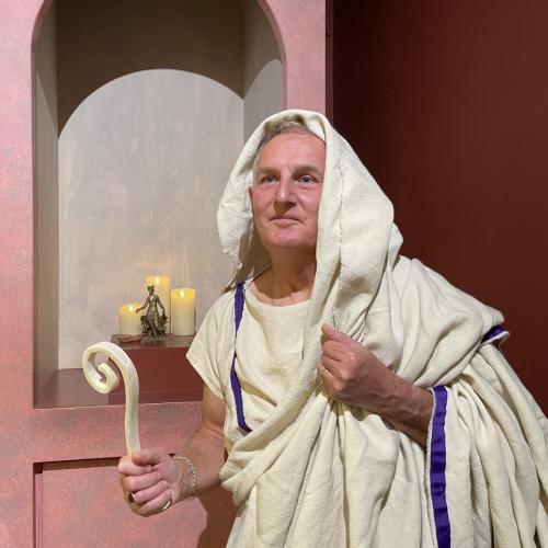 Roman priest re-enactor in front of shrine