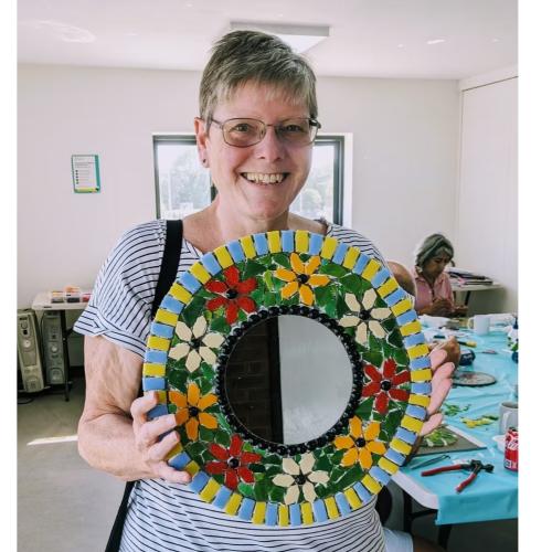 woman holding up  mosaic mirror