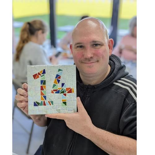 man holding mosaic door number