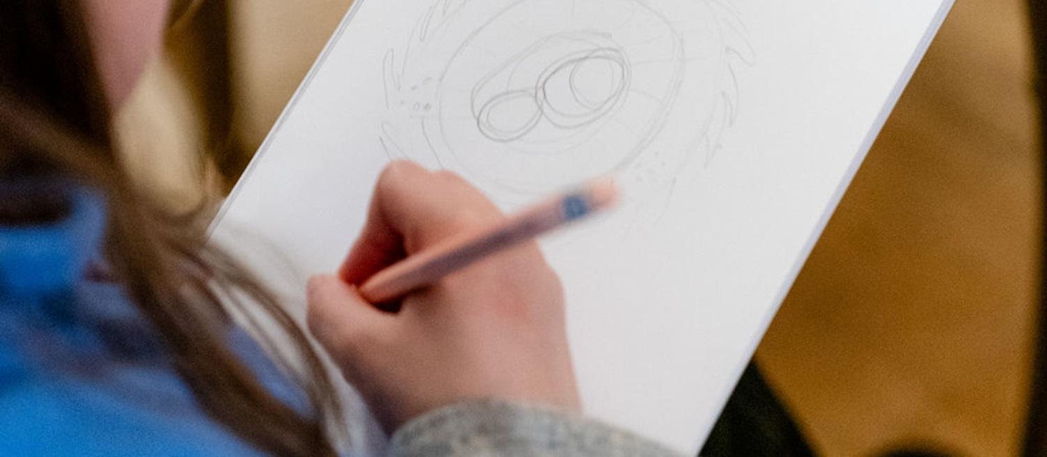 child's hand holding pencil and drawing on 
