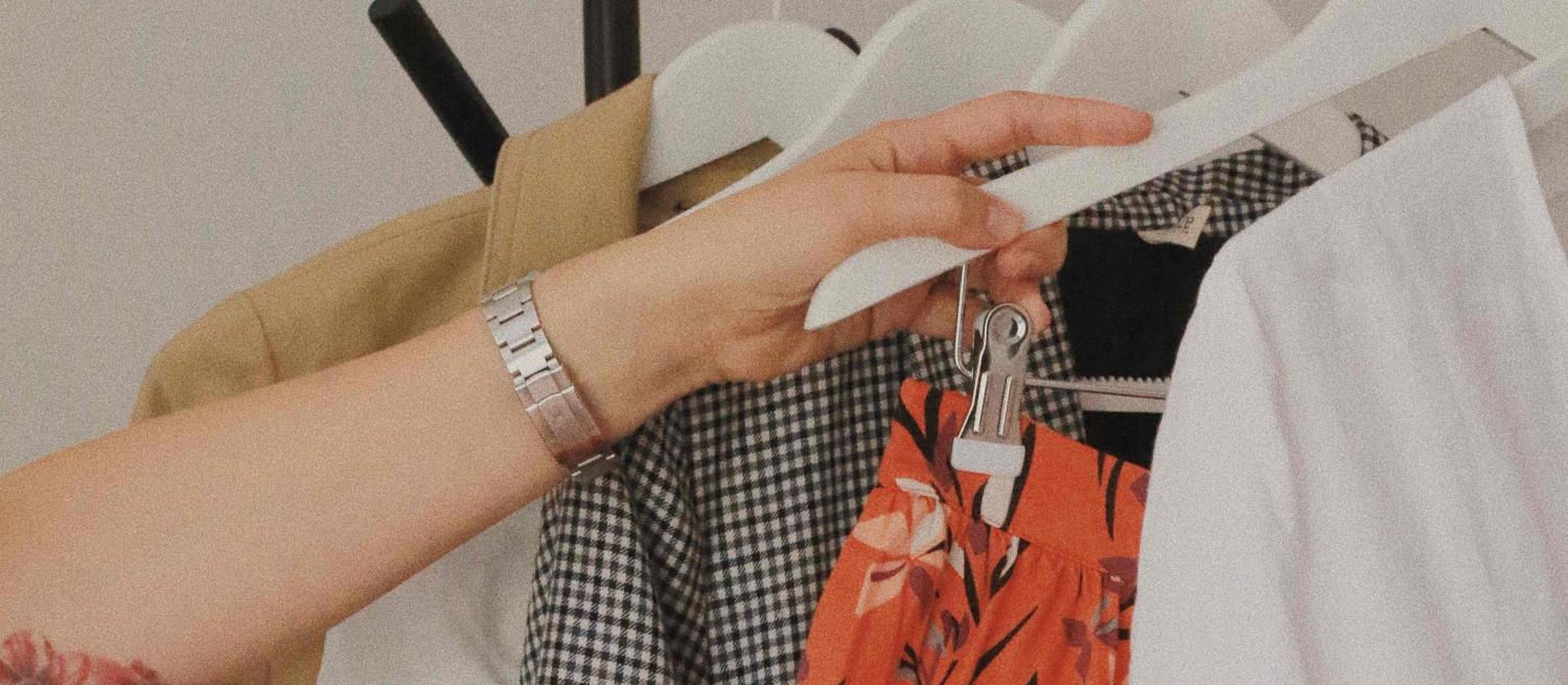 Hand taking a clothes hanger off a rail