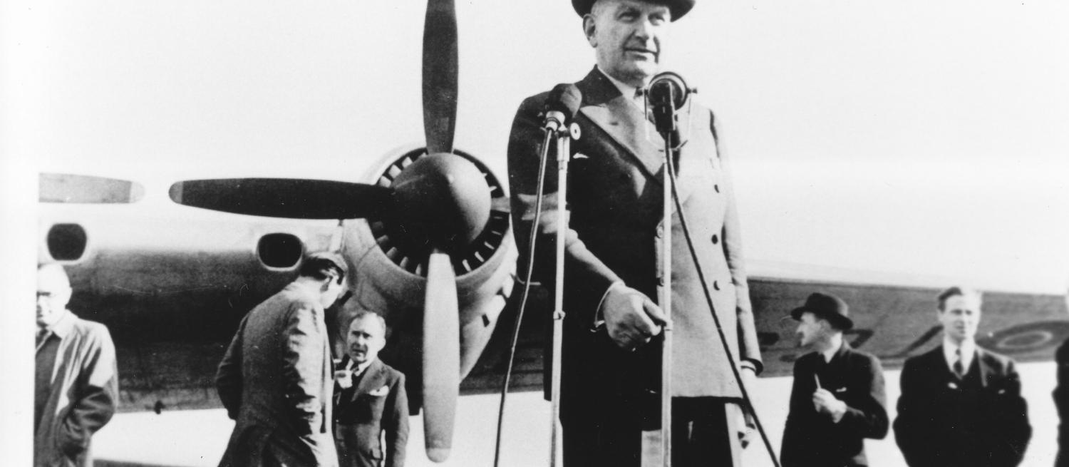 Sir HP standing in front of a plane wearing a hat
