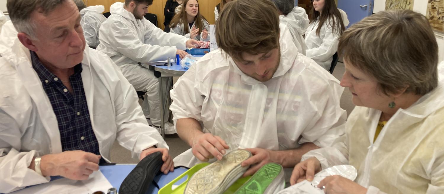three people in CSI suits examining shoe prints