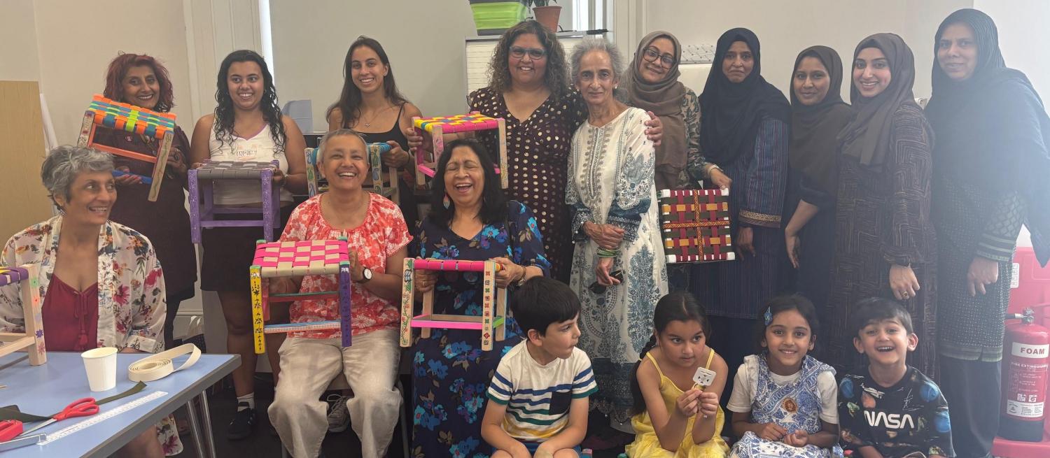 Group of women arranged in a line with woven stools in front of them