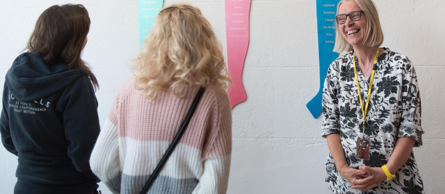 Two visitors talking to a volunteer in front of an art installation by Lyndall Phelps