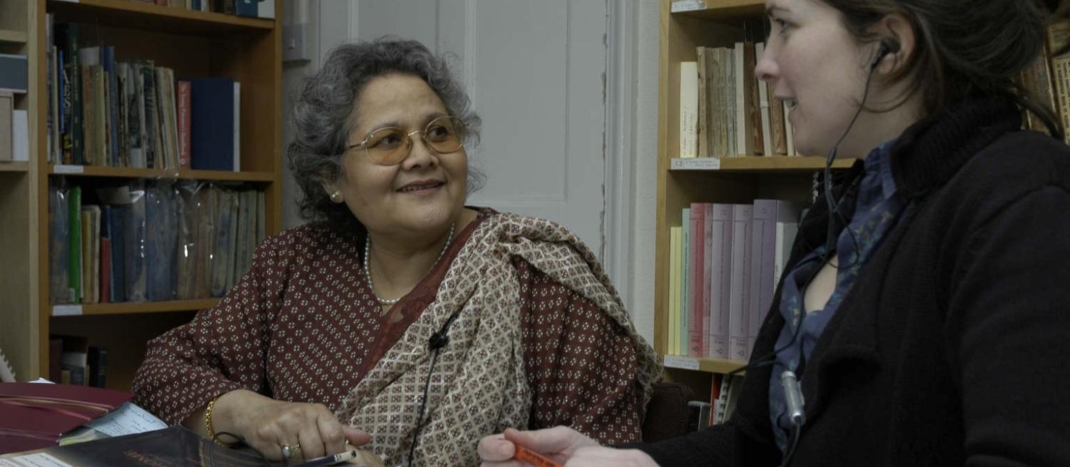 Colour photograph of a woman in a sari being interviewed by a younger woman in a black top