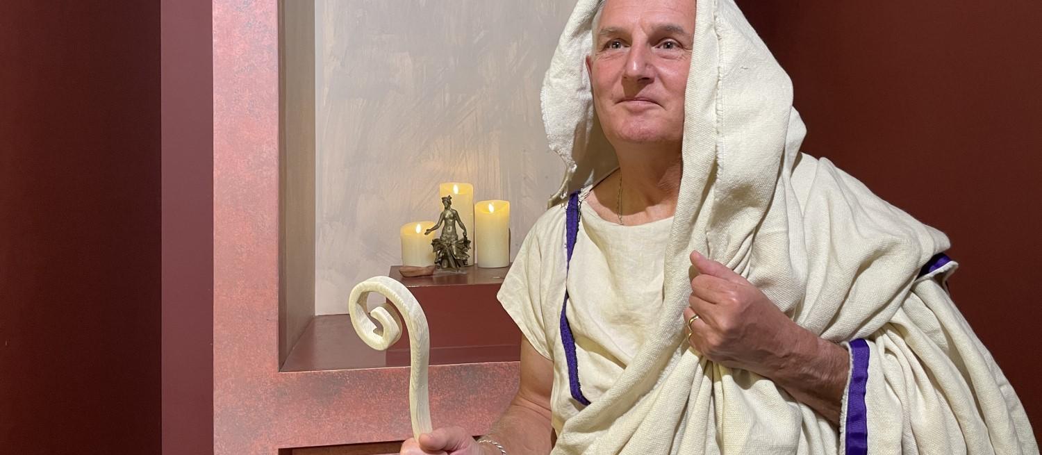 Roman priest re-enactor in front of shrine