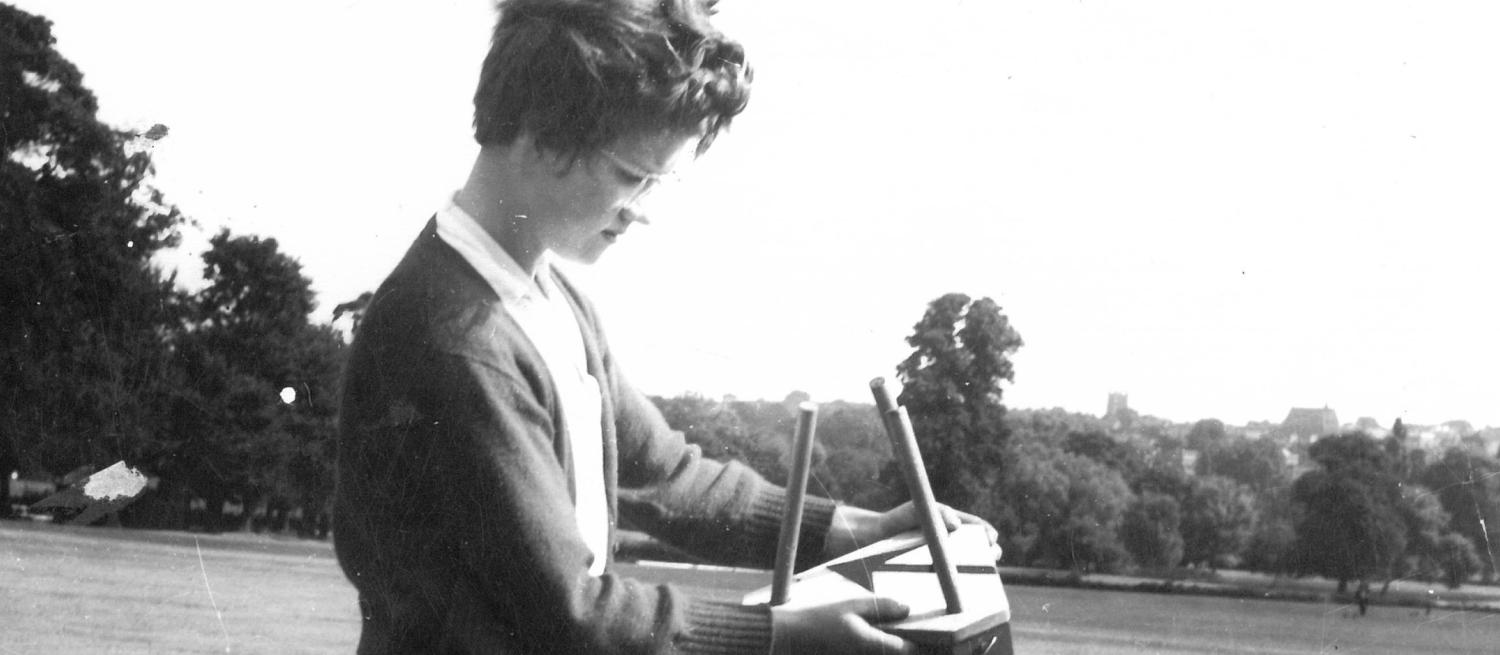 black and white photograph of a woman in a field with short hair and glasses