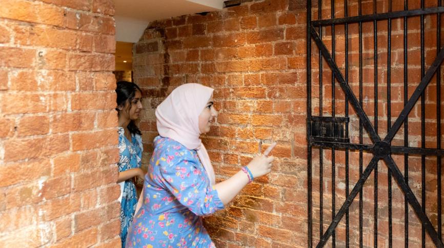 a woman wearing a head scarf exploring the cells at St Albans Museum + Gallery