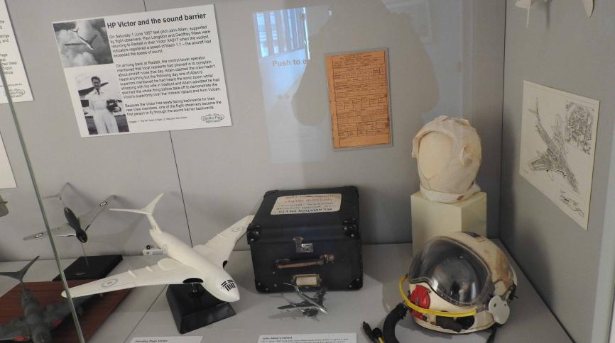 John Allam's helmet and flight cap in a museum case