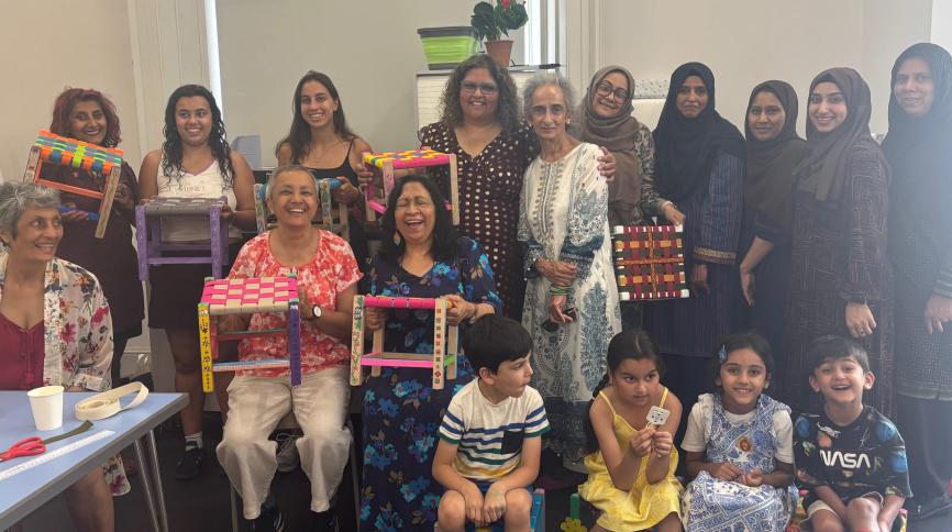 Group of people posed for a photograph with woven stools that they have made in a workshop