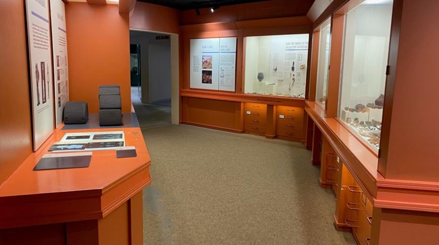 An orange room with a display case. You can see an arch made out of large black foam bricks.