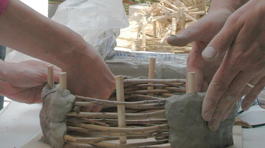clay being pressed into the wooden frame of a miniature roundhouse