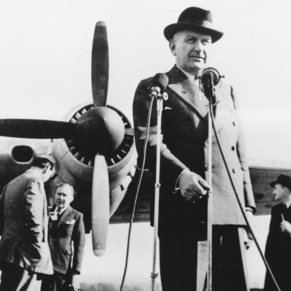 Sir HP standing in front of a plane wearing a hat