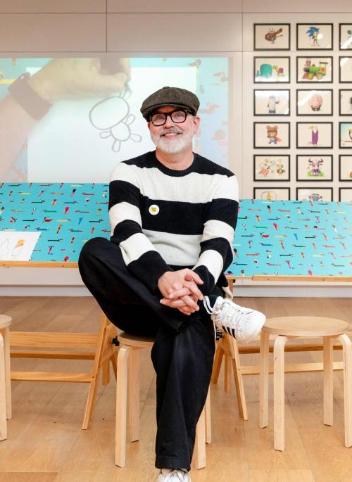Rob Biddulph sitting in an exhibition of his work