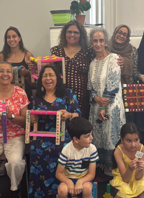 Group of women arranged in a line with woven stools in front of them