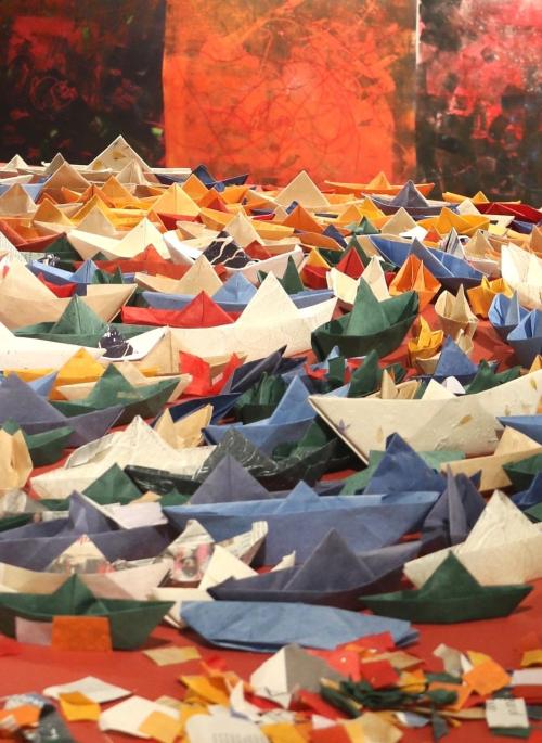 Multicoloured paper boats in an art installation on a red base