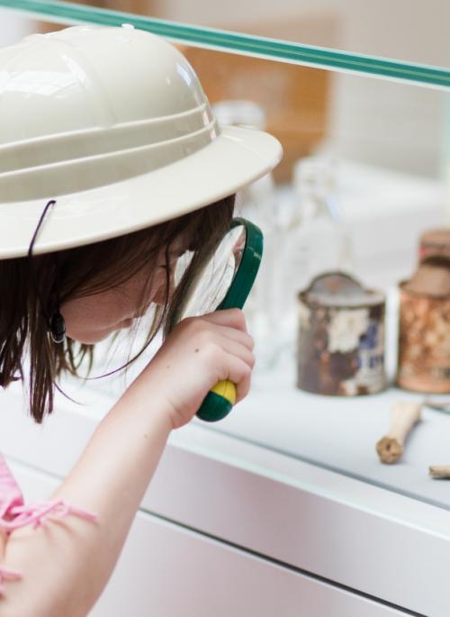Child looking at objects through a magnifying glass