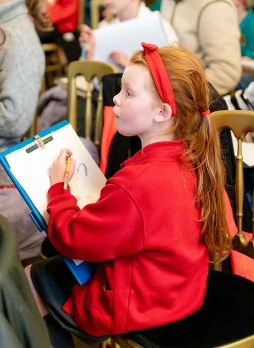 child in red drawing on clipboard