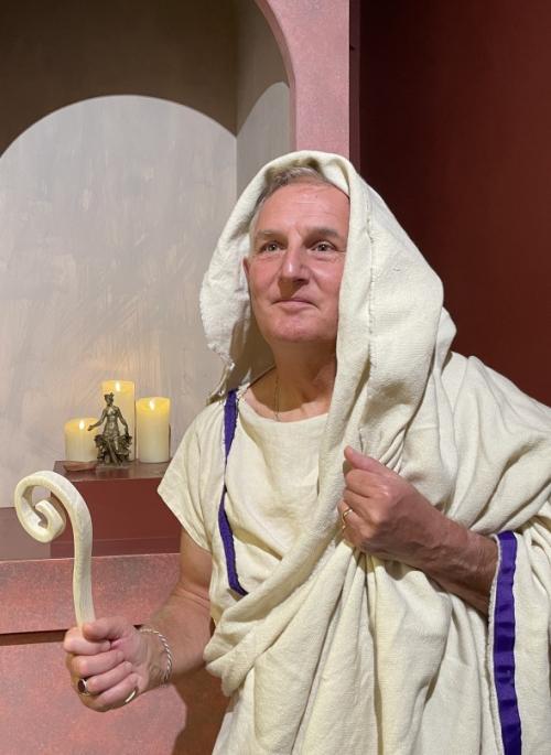 Man dressed as Roman priest in front of shrine